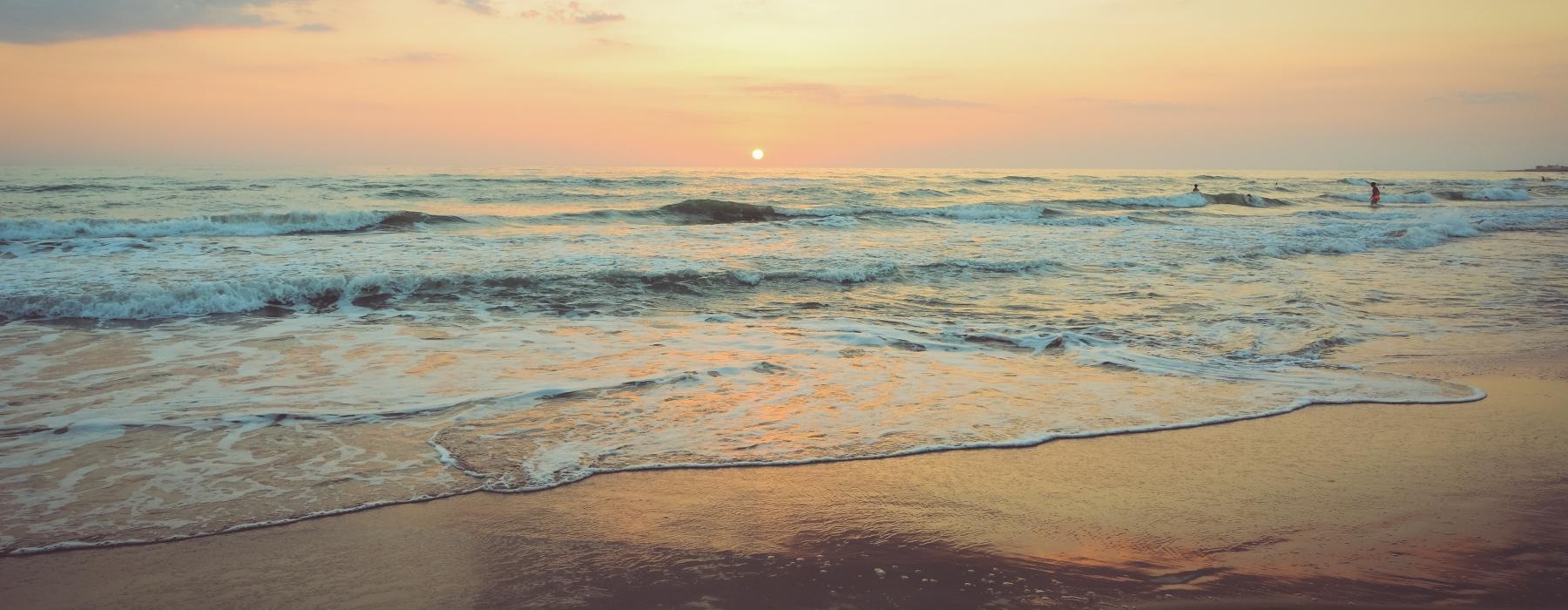a beach with waves and a sunset